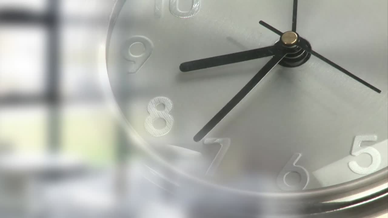 Animación de un reloj moviéndose sobre una oficina difuminada al fondo