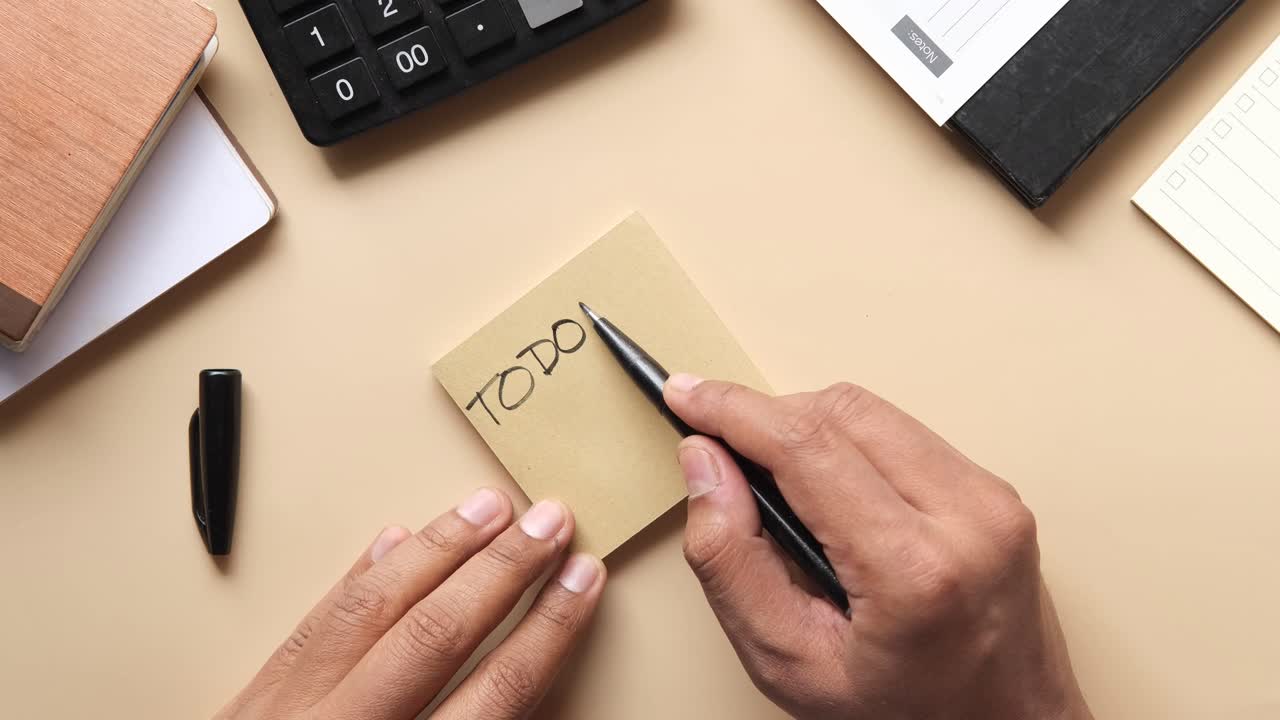 Person writing on a sticky note on a desk