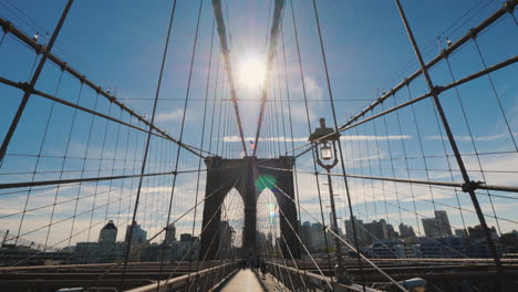 Walk-Along-The-Brooklyn-Bridge-From-Manhattan-To-Brooklyn-The-Sun-At-Its-Zenith-Shines-In-Frame-Pov-