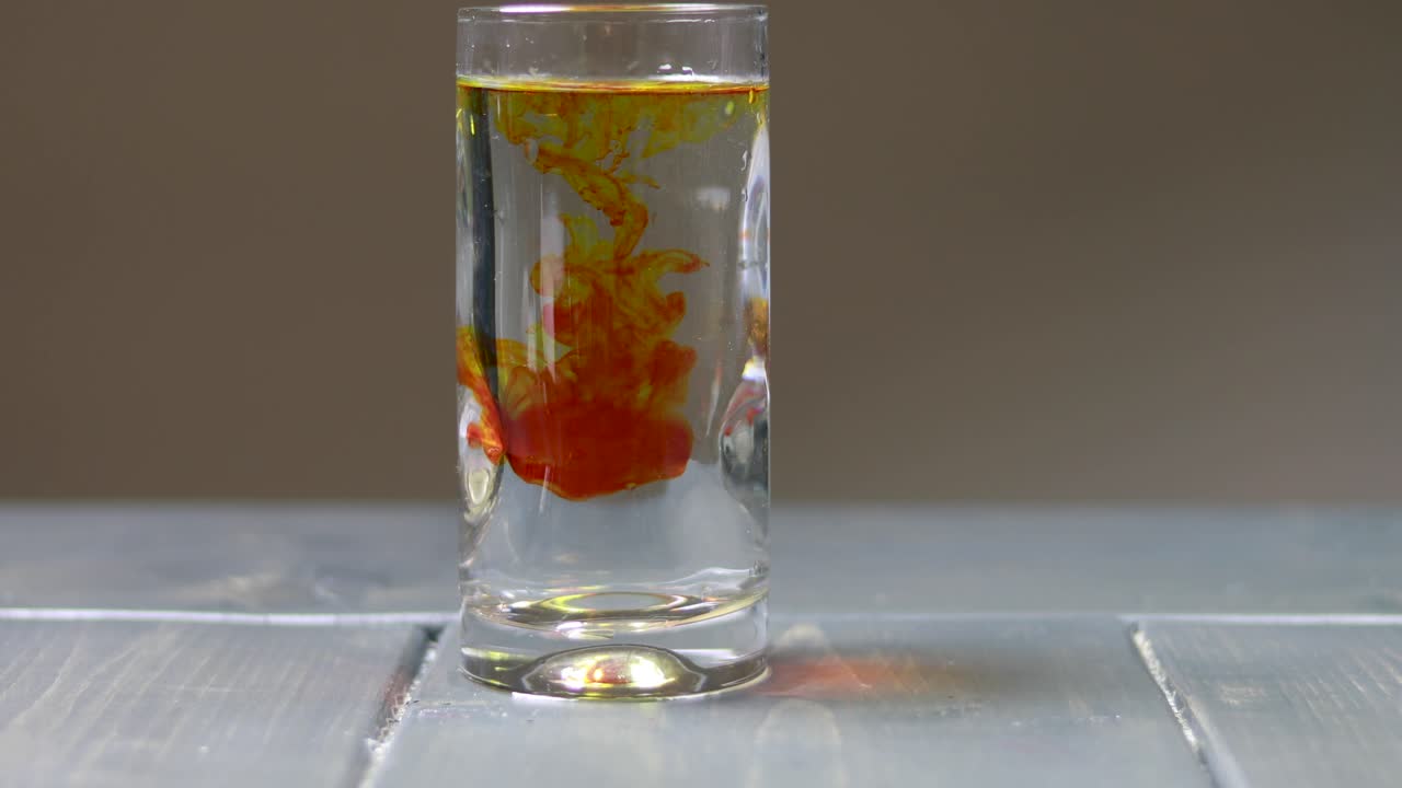 dejar caer gotas de tinte amarillo en un vaso de agua