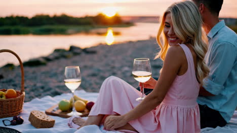happy couple enjoying a sunset picnic by the river with wine