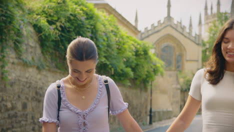 same sex female couple sightseeing as they hold hands and walk around oxford uk