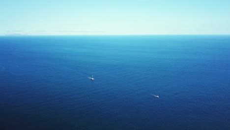 aerial view of two yachts sailing on the calm, vast blue ocean, creating a tranquil scene of maritime adventure near funchal, madeira island, portugal, with the horizon blending with the sky
