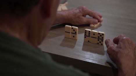 older male places a new domino onto the current game table