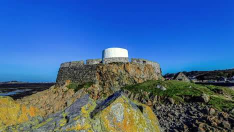 hiperlapso de la antigua pared de piedra en roca en un paisaje costero de guernsey en un día soleado