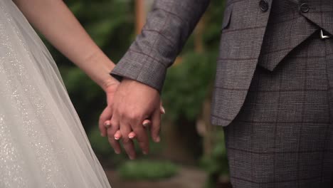 the bride and groom hold hands while walking in nature