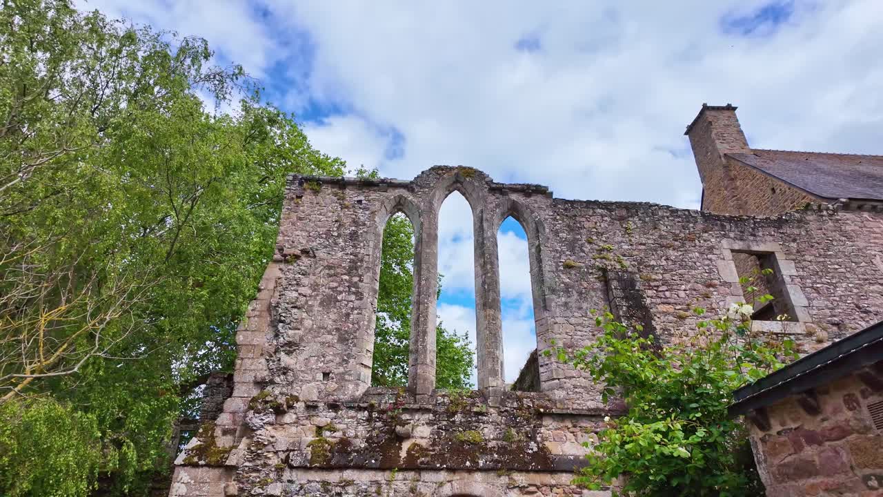 Camera pullout from Beauport Abbey in Paimpol, France—Gothic ruins framed by coastal gardens, forest edge, and the Bay of Launay in a layered monastic and maritime landscape