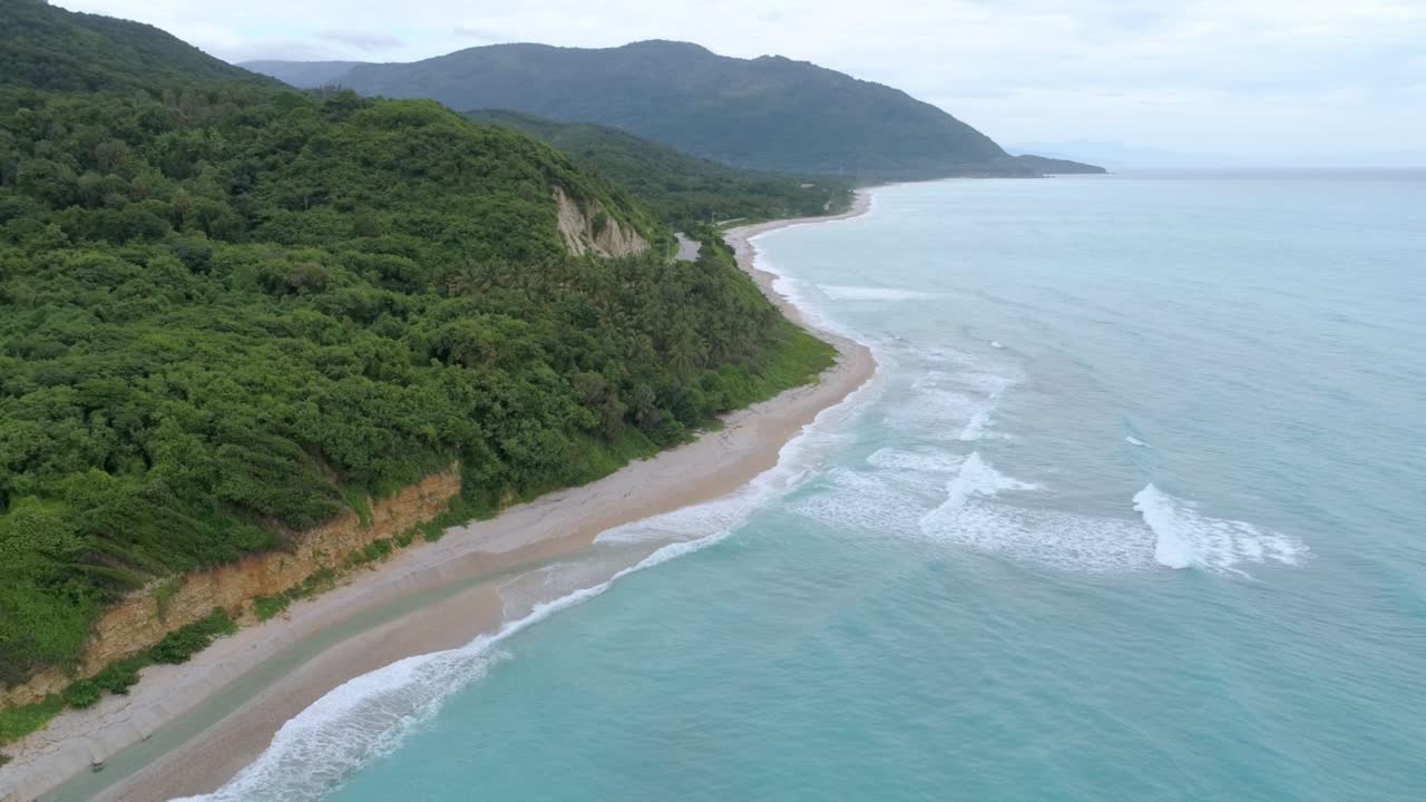 toma escénica con drones viendo el río los patos uniéndose a la playa en barahona, república dominicana, día nublado, grandes montañas verdes