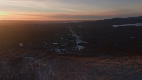 aerial view of snowy mountain forest and road at the countryside in southern quebec, canada at sunset in winter