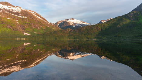 timelapse of a mirror-like lake and dramatic mountains bathed in midnight sun, lofoten islands, norway