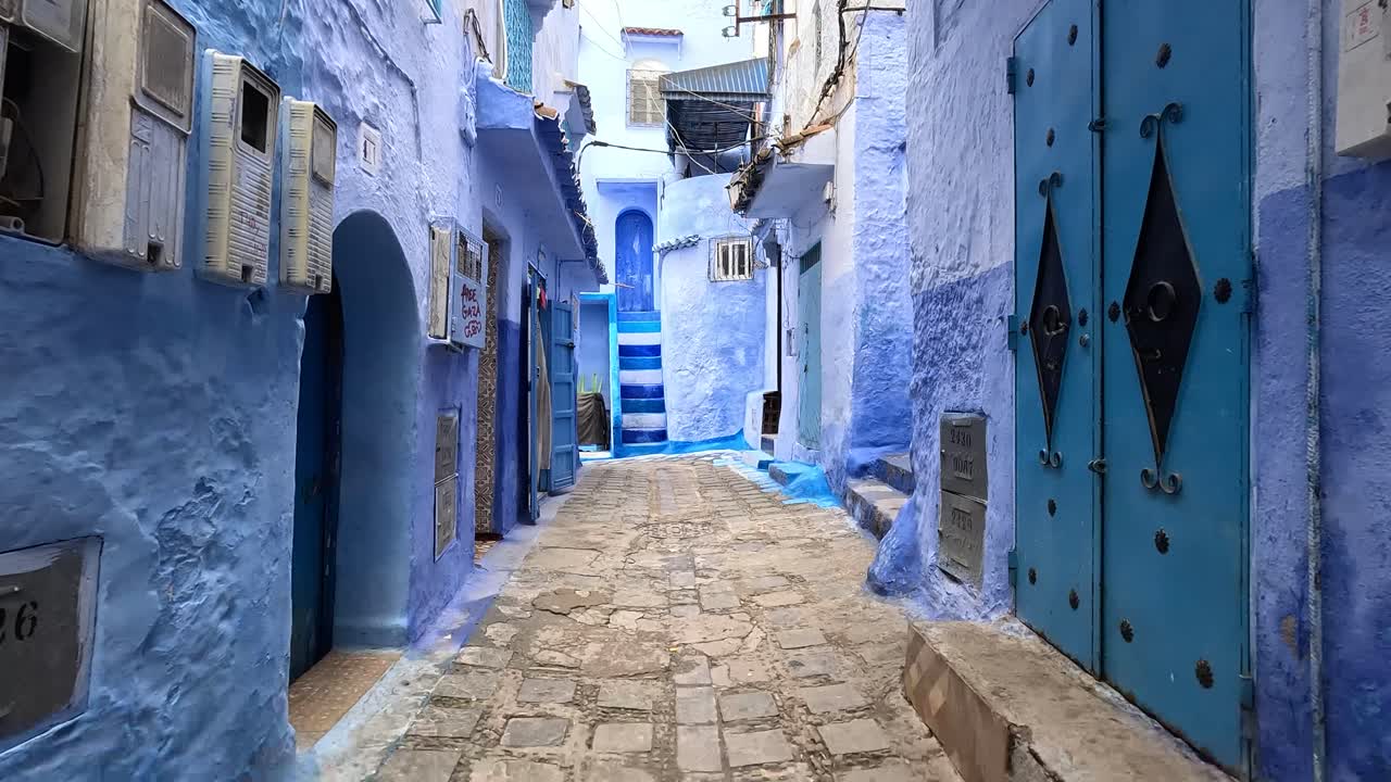 Gåtur på gaden langs de blåmalede bygninger i Chefchaouen, Marokko. - POV-optagelse