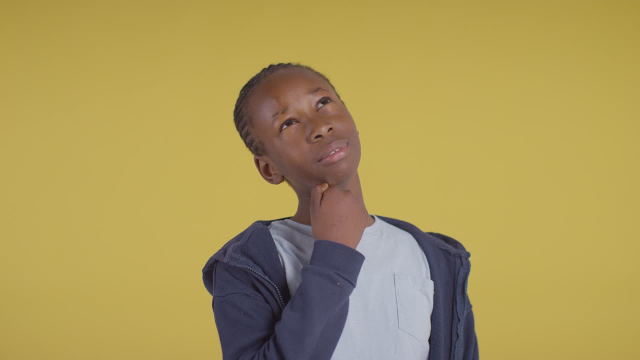 Studio Portrait Of Young Boy Thinking Against Yellow Background 1