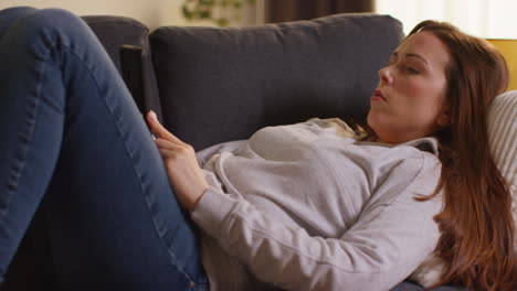 Close-Up-Of-Woman-Lying-On-Sofa-At-Home-At-Streaming-Or-Watching-Movie-Or-Show-Or-Scrolling-Internet-On-Mobile-Phone-4