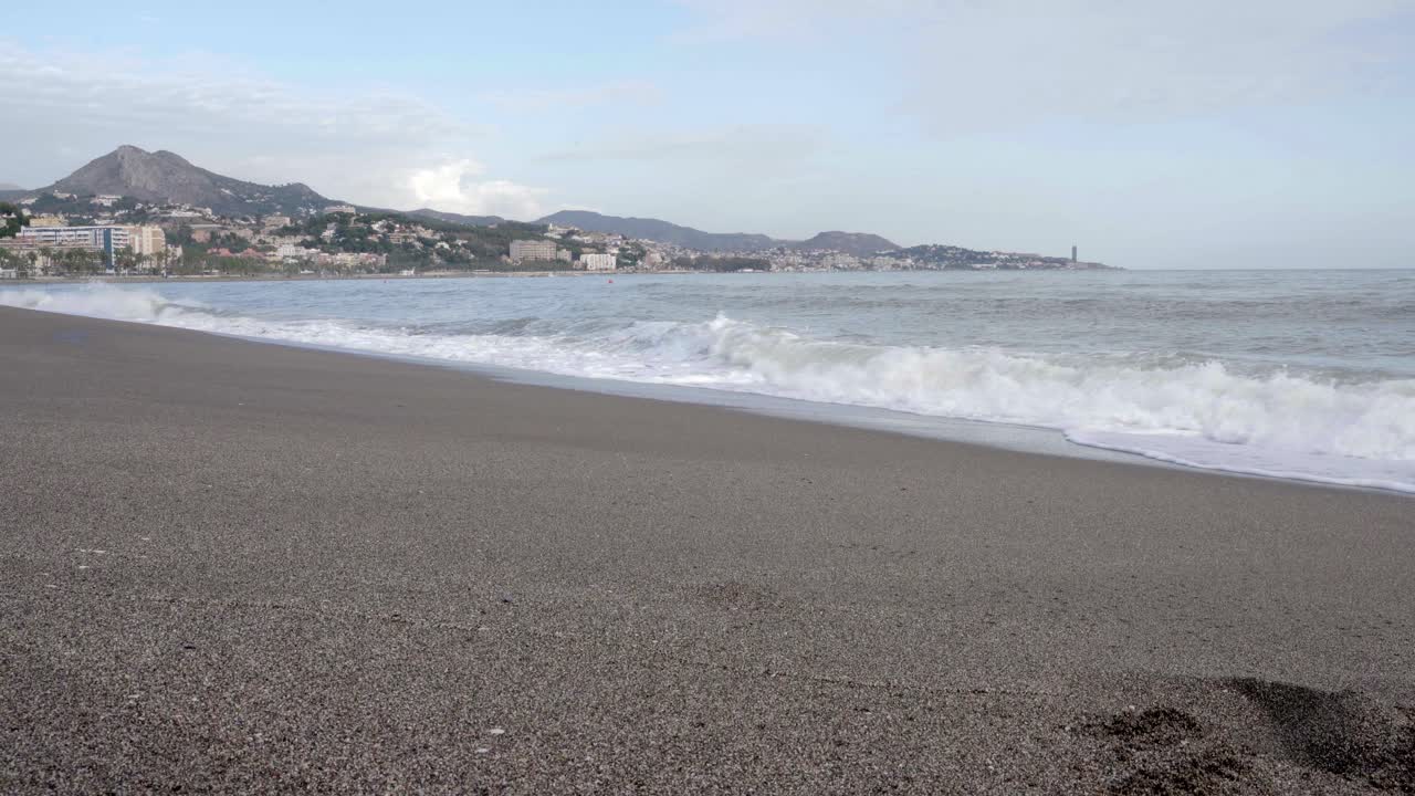 Serene Beach Landscape with Ocean Waves and Distant City