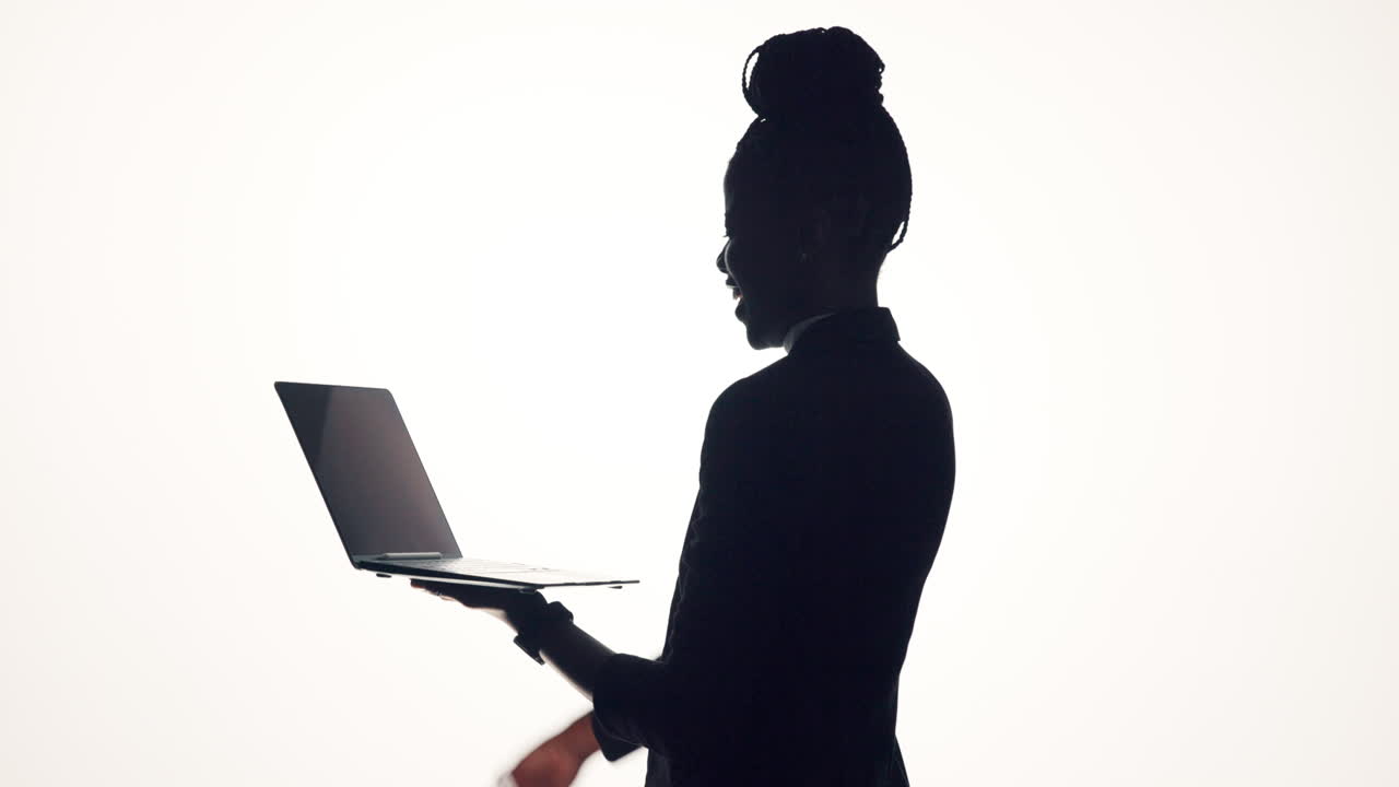 Silhouette of a successful businesswoman celebrating with her laptop