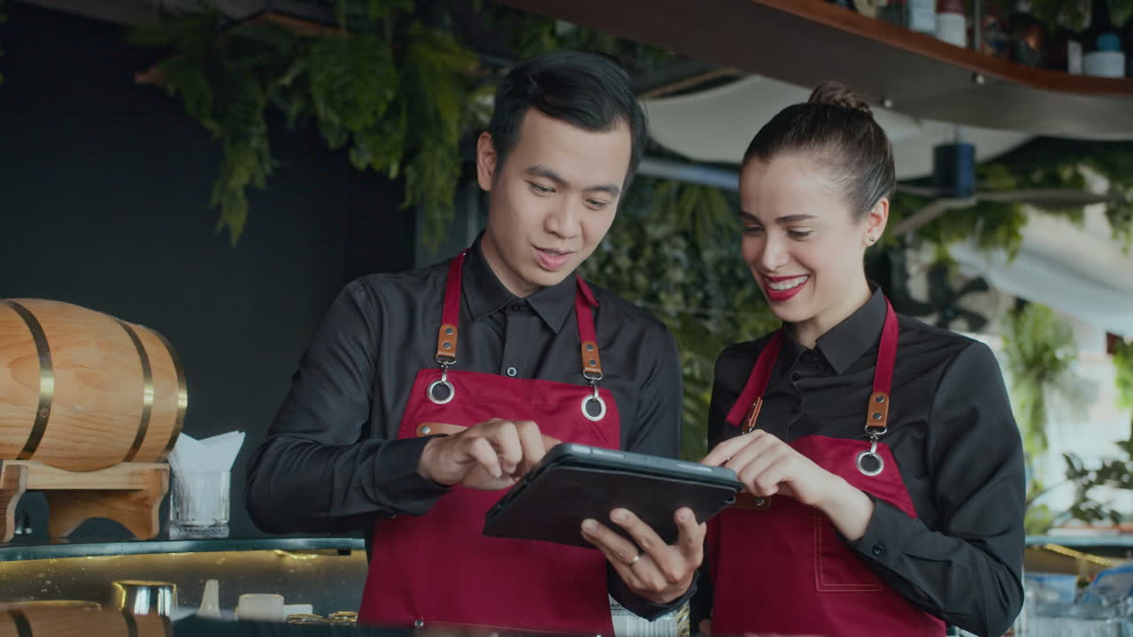 Diverse Waiters Looking at Guests Orders on Tablet PC