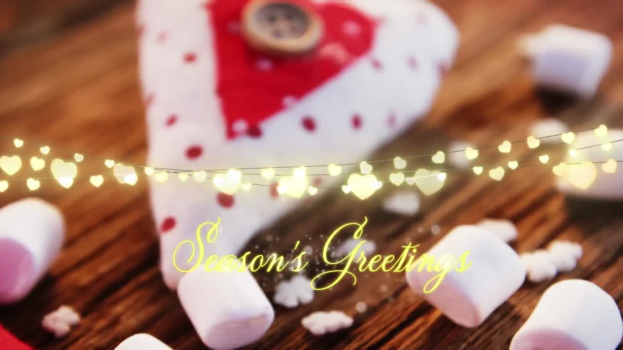 Animation of text, season's greetings, with string lights, marshmallows and christmas decorations