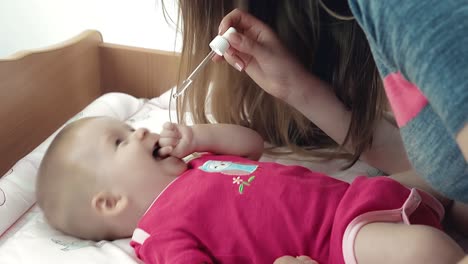 mother gives baby girl lying on diaper table sweet medicine