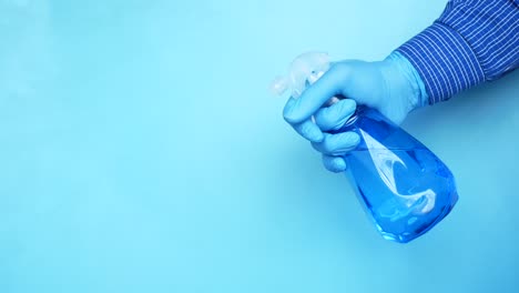 person in blue gloves holding a blue spray bottle