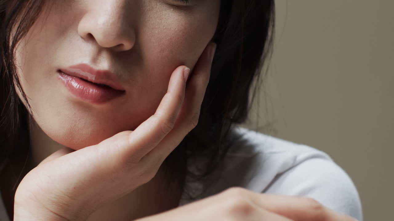 mujer asiática con cabello negro y maquillaje tocando la cara, copiar el espacio, cámara lenta