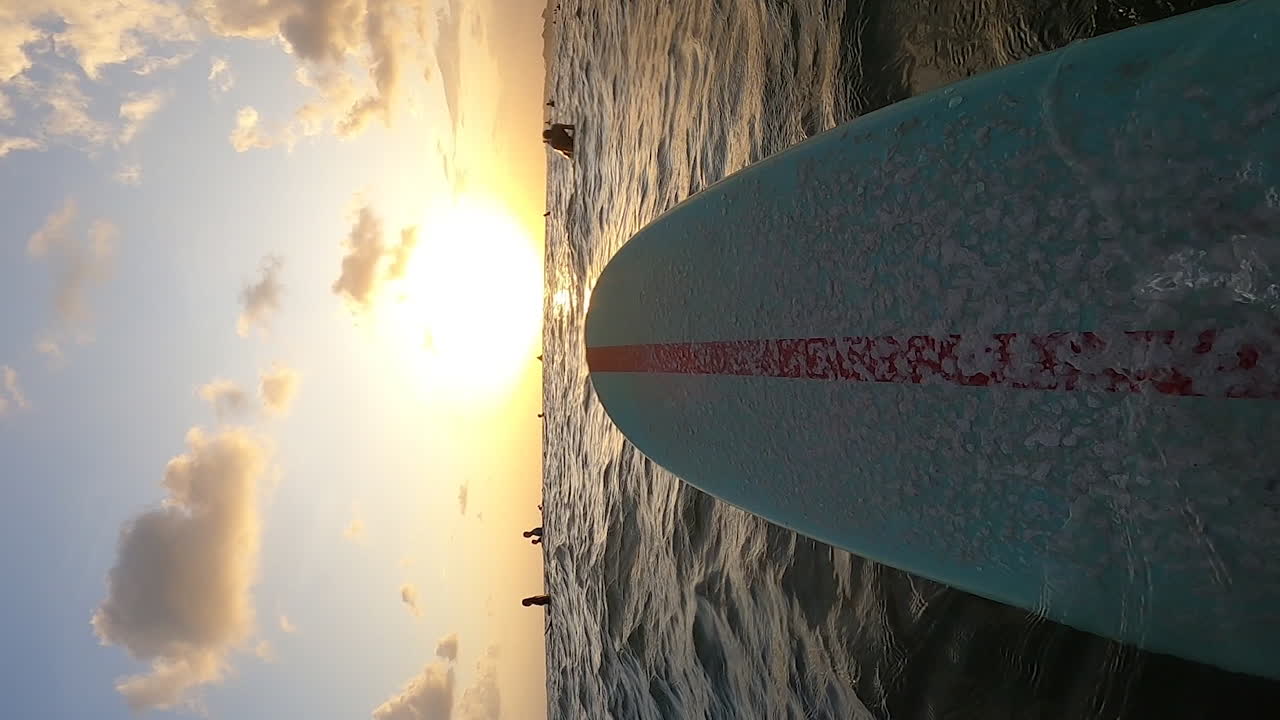 Scatto verticale di una tavola da surf blu con linea rossa che galleggia sulla superficie del mare a Canggu, Bali, Indonesia