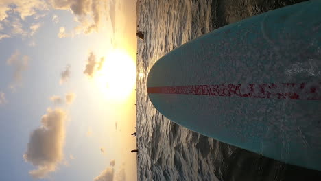 Toma-Vertical-De-Una-Tabla-De-Surf-Azul-Con-Una-Línea-Roja-Flotando-En-La-Superficie-Del-Mar-En-Canggu,-Bali,-Indonesia