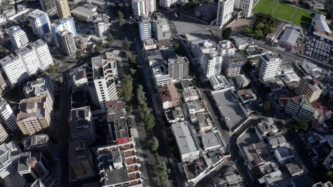 Drone shot of the city of Quito, Ecuador. Overlooking buildings in the street La Republica and seis de diciembre. Empty streets with trees and houses.