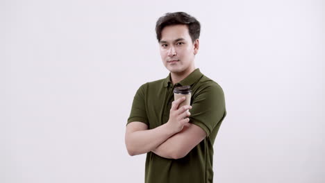 handsome young man in an olive green shirt standing confidently with a paper coffee cup, reflecting the spirit of entrepreneurship and self-made success.