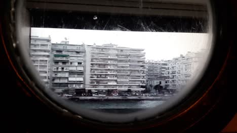 view of thessaloniki shore as seen through a porthole on a ship