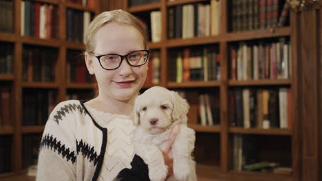 Glückliches-Mädchen-In-Der-Bibliothek-Sind-Ein-Mädchen-Und-Ein-Welpe-Mit-Brille.-Lieblingshaustiere-Und-Bildung