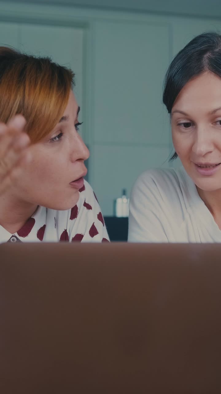 Two women work together on laptop during the daytime