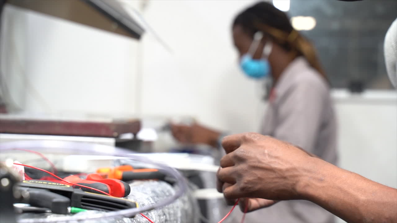 gente sentada en la mesa cortando cables y trabajando con las manos