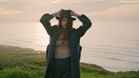 modelo sensual caminando por la colina cerca del hermoso océano en primer plano. mujer posando al atardecer.