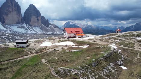 Aerial-flying-backwards-from-Antonio-Locatelli-hut-and-tourists-nearby