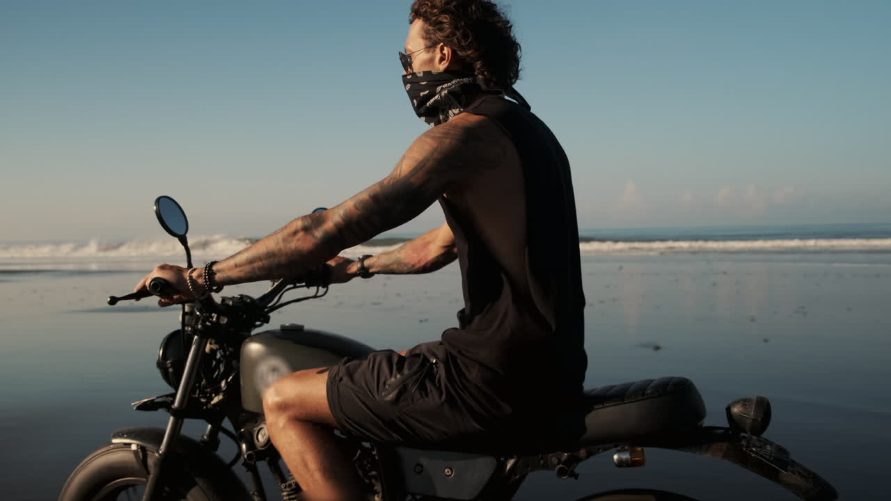 Motorcycle rider on a beach at sunset
