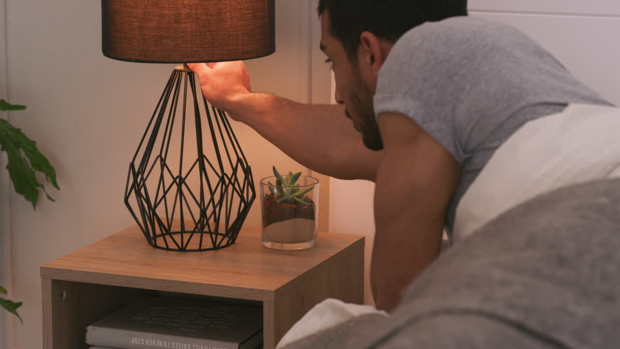 Man sleeping in bedroom next to lamp