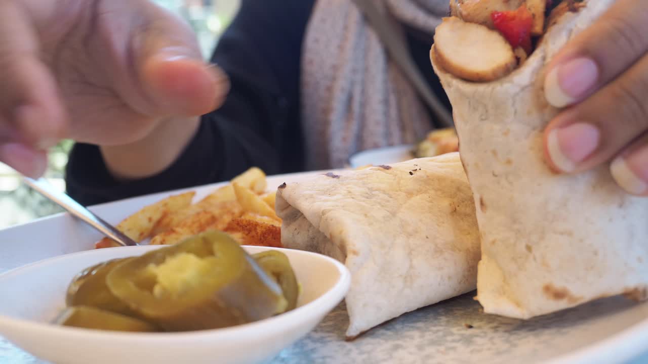 A close up of a wrap with jalapeños and french fries