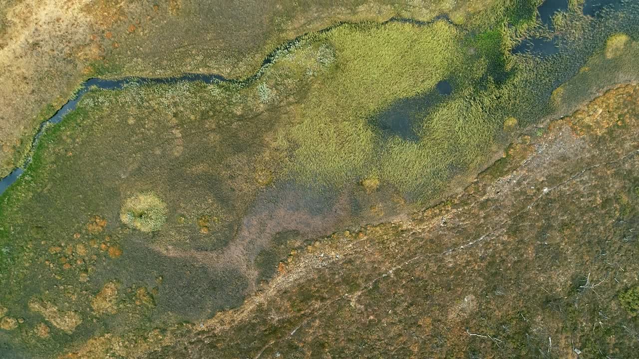 dron volando sobre un verde paisaje montañoso escarpado con lago, río y bosque exuberante.