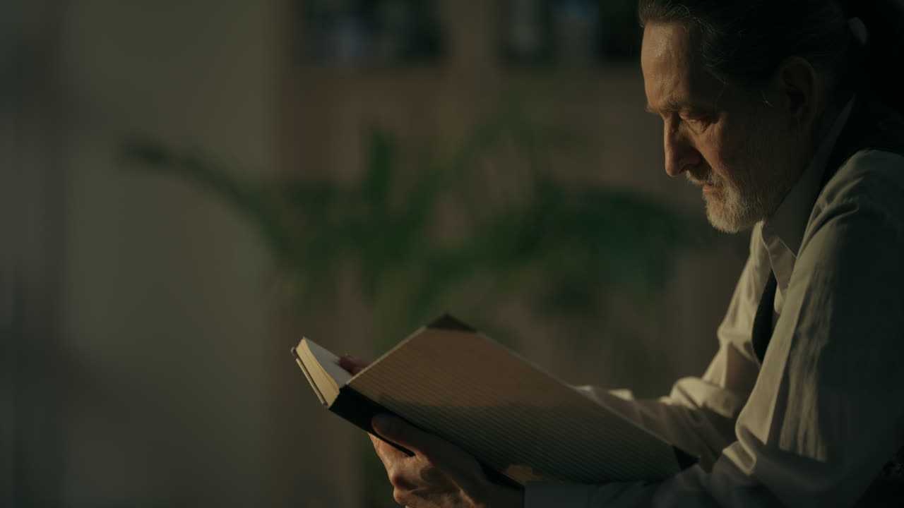 Older Man Reading a Book and Turning Pages