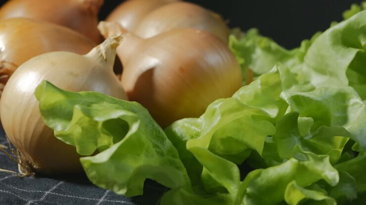 Close-up, rotation, juicy green salad leaves and golden onions, rotate