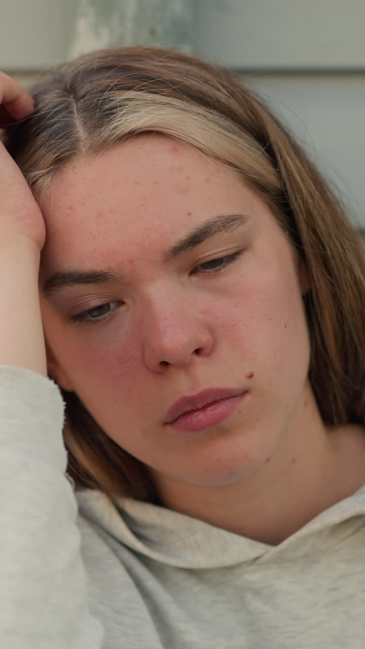 primer plano de una joven que descansa la cabeza sobre la mano con una expresión pensativa, mostrando una profunda contemplación, la suave luz del sol crea calor en el fondo