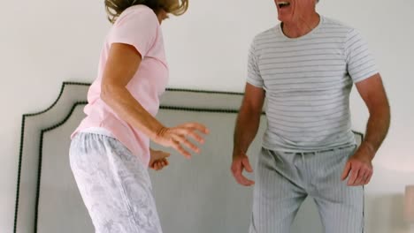 Happy-senior-couple-dancing-on-bed