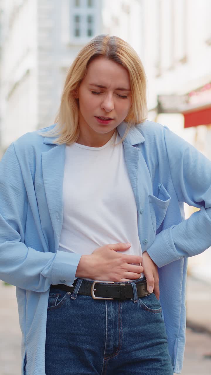Sick ill woman suffering from period cramps stomach ache menstrual pain gastritis on city street
