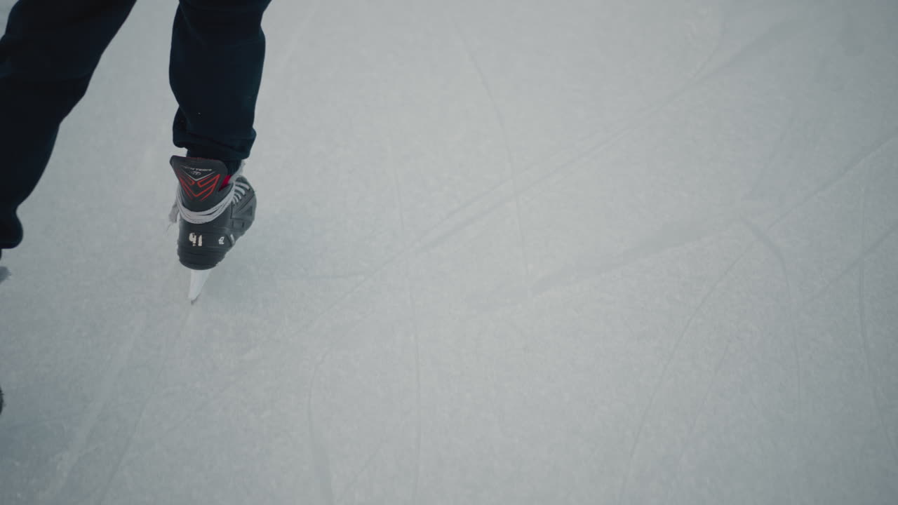 experienced skater gliding skillfully on pristine ice rink under pale winter sky crisp cold atmosphere smooth blade tracks evoking serene motion focused balance and athletic grace on frozen surface