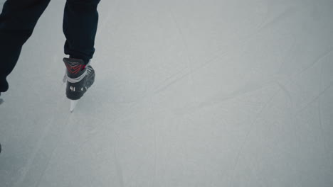 experienced skater gliding skillfully on pristine ice rink under pale winter sky crisp cold atmosphere smooth blade tracks evoking serene motion focused balance and athletic grace on frozen surface
