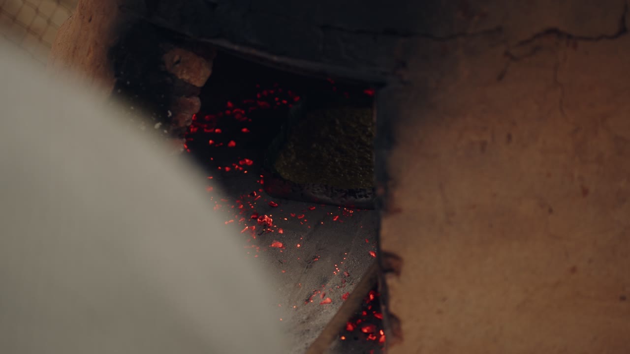 Placing 2 baking trays with paraguayan soup, into the tatakua with coals