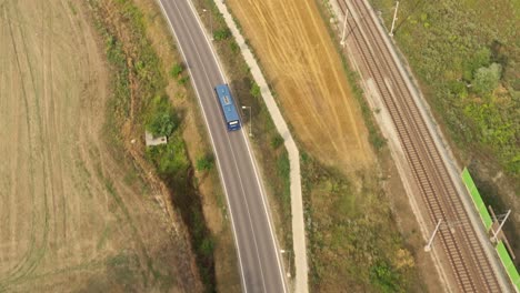 aerial top shot of the blue bus in rural countryside on the asphalt road