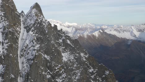 slow-motion-panoramic-view-from-mountain-top-winter-season-starting-in-the-alps,-snowy-peaks-in-background