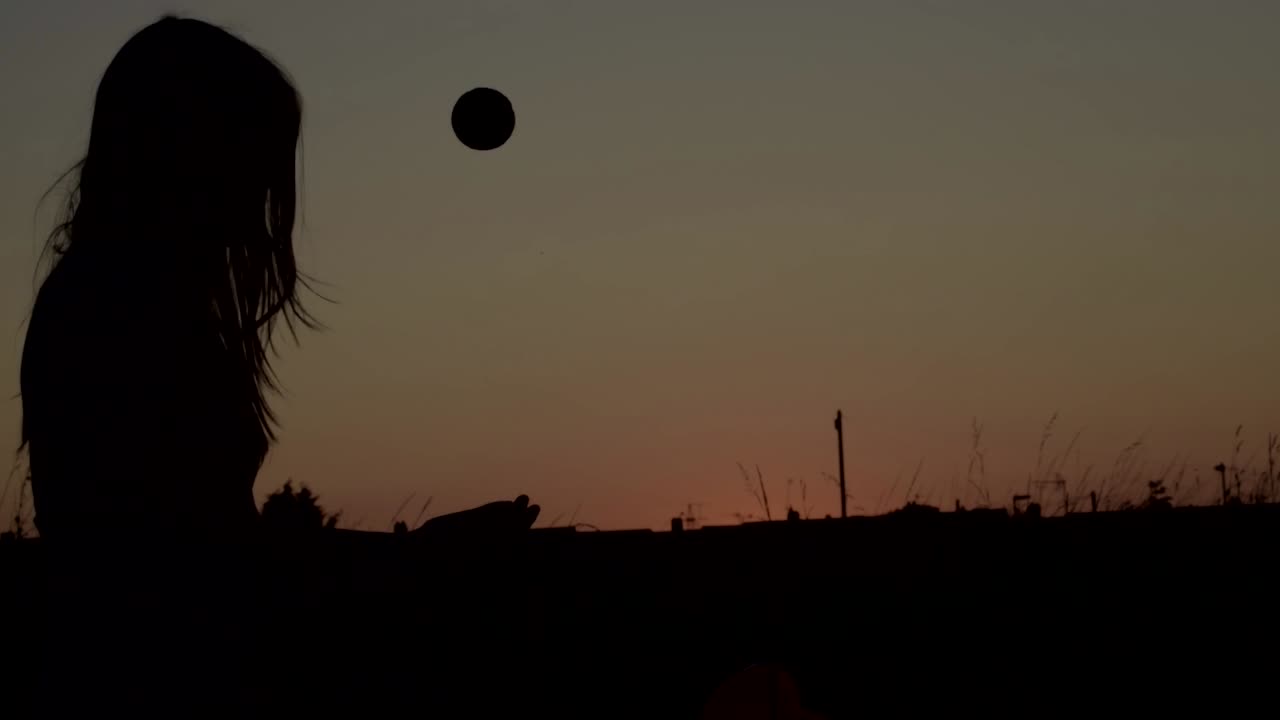 일몰-1에서 공중으로 공을 던지는 고독한 실루엣의 여성