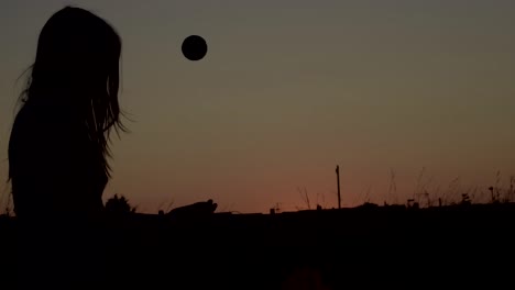 mujer en silueta de soledad lanzando una pelota al aire al atardecer-1